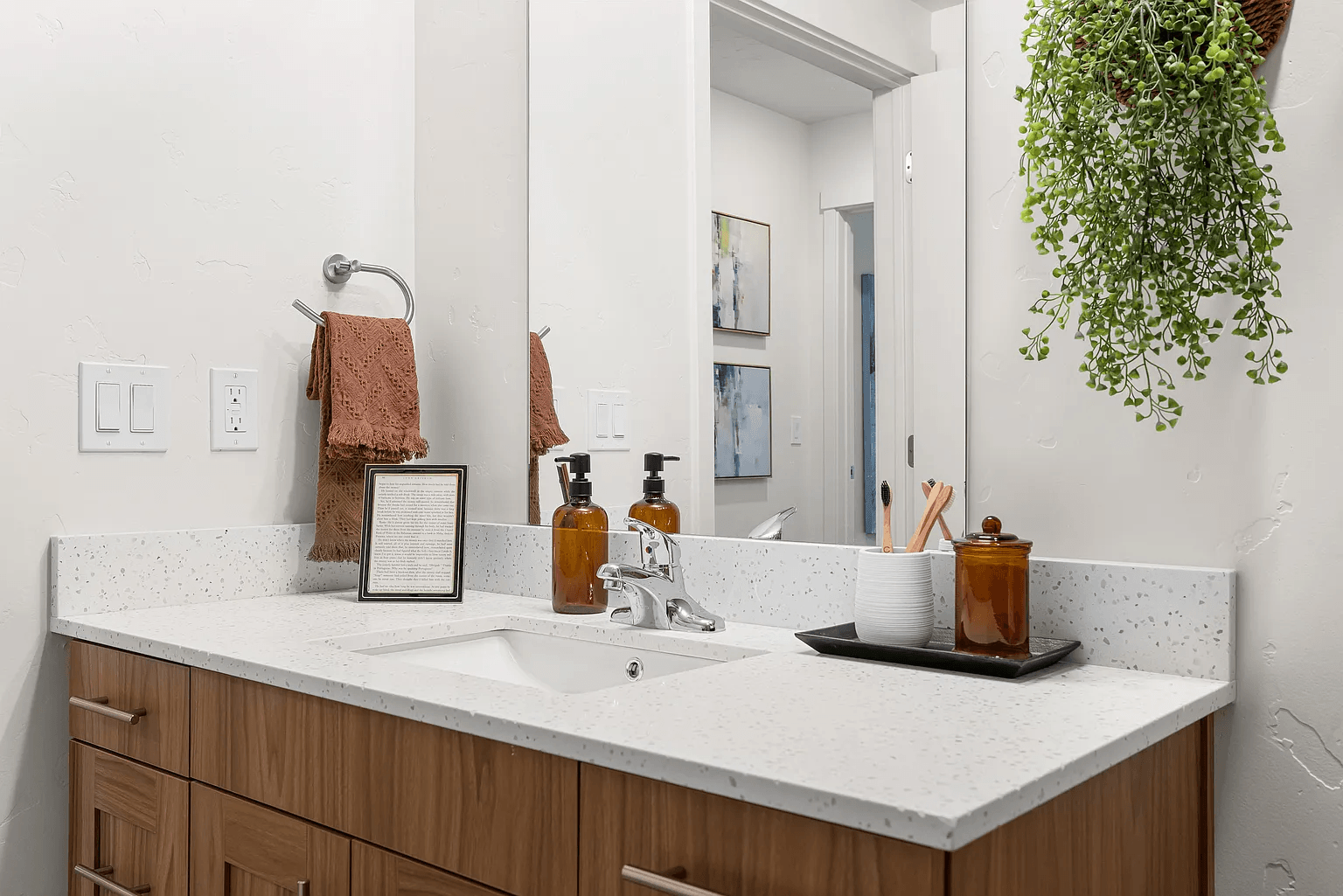 A bathroom with a white counter top and a mirror.